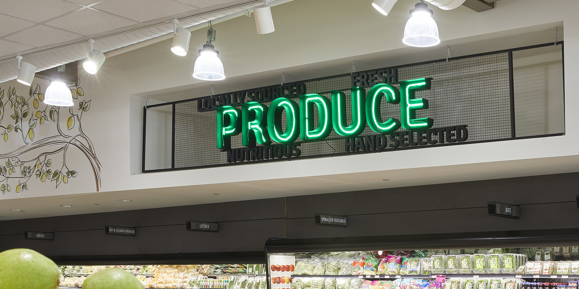 A neon produce sign in a grocery store.